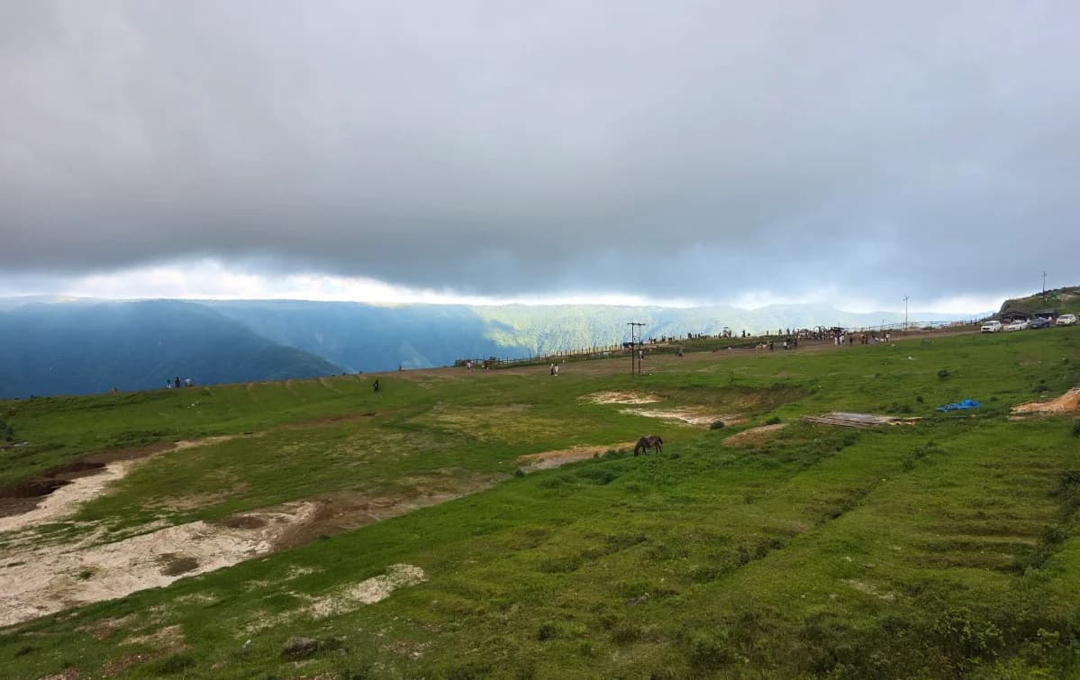 Open grassy ground and established paths beneath grey clouds at Laitlum
